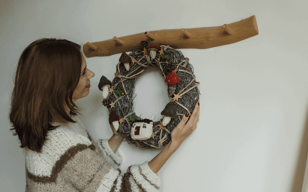 A woman hanging a wreath on the wall