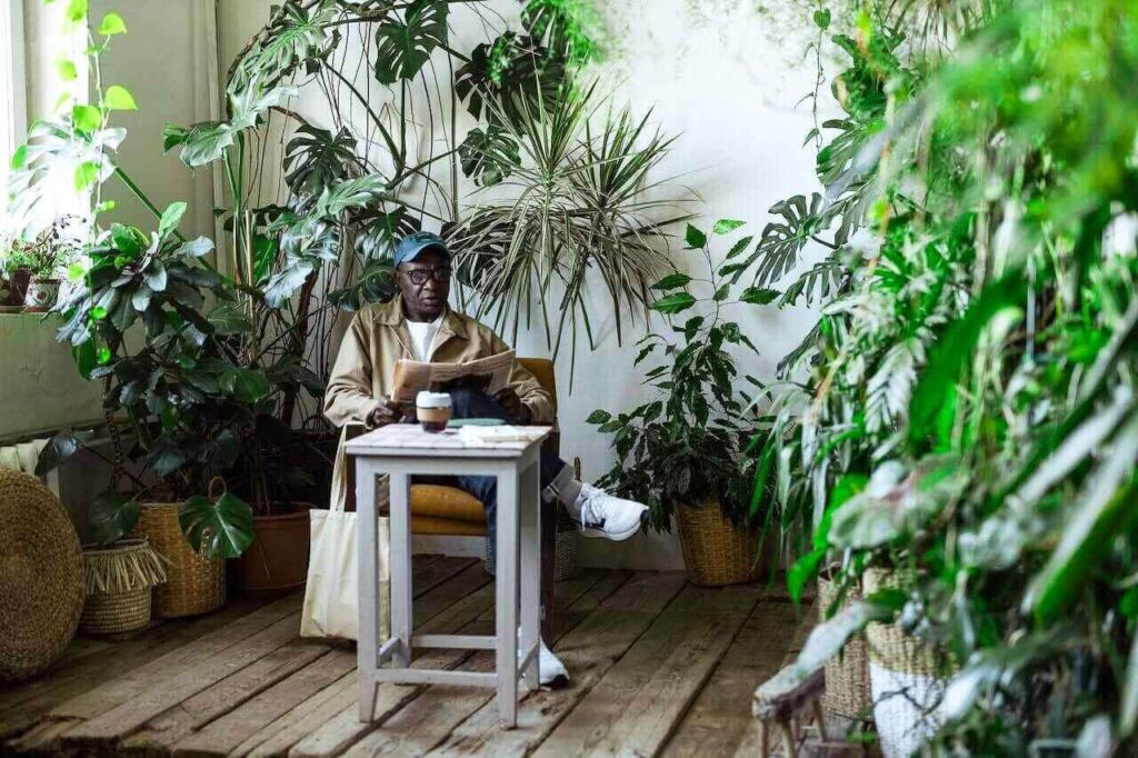man relaxes while reading a newspaper in his winter garden