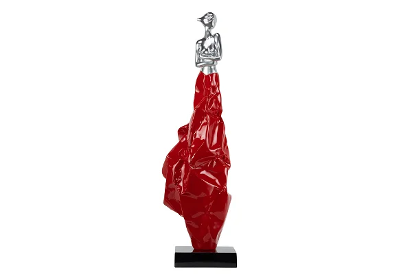 Red elongated sculpture, silver figure on top, contemporary art.