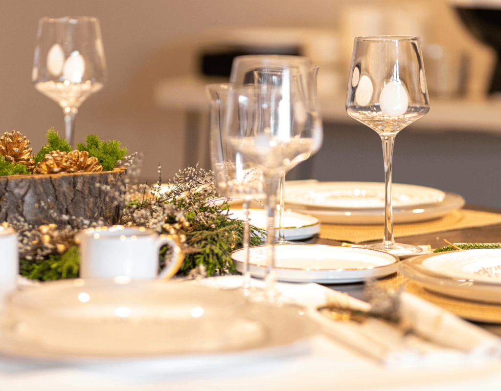 Elegant dining table setting with crystal glassware and gold-trimmed plates on a festively decorated table.