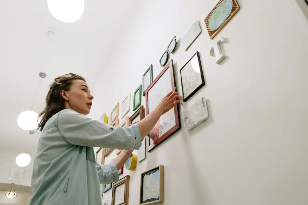 Woman hanging pictures on the wall to create a gallery wall
