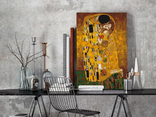 Modern interior setting featuring Gustav Klimt's 'The Kiss' canvas resting on a desk, with decorative objects and industrial-style elements.