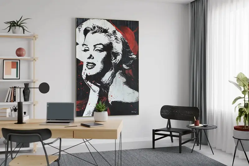 A canvas hung in an office room with an image of a woman against a red background.