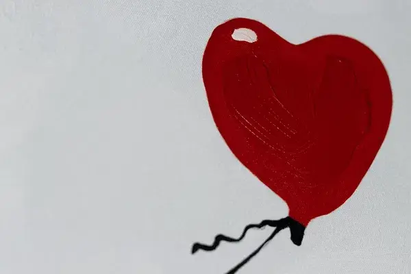 An image of a red heart balloon in white background