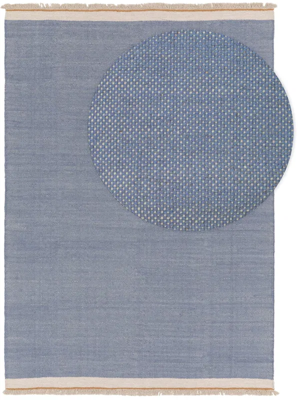 Calming blue rug with a woven circular design in the corner, complete with fringe edges for a simple, modern look.