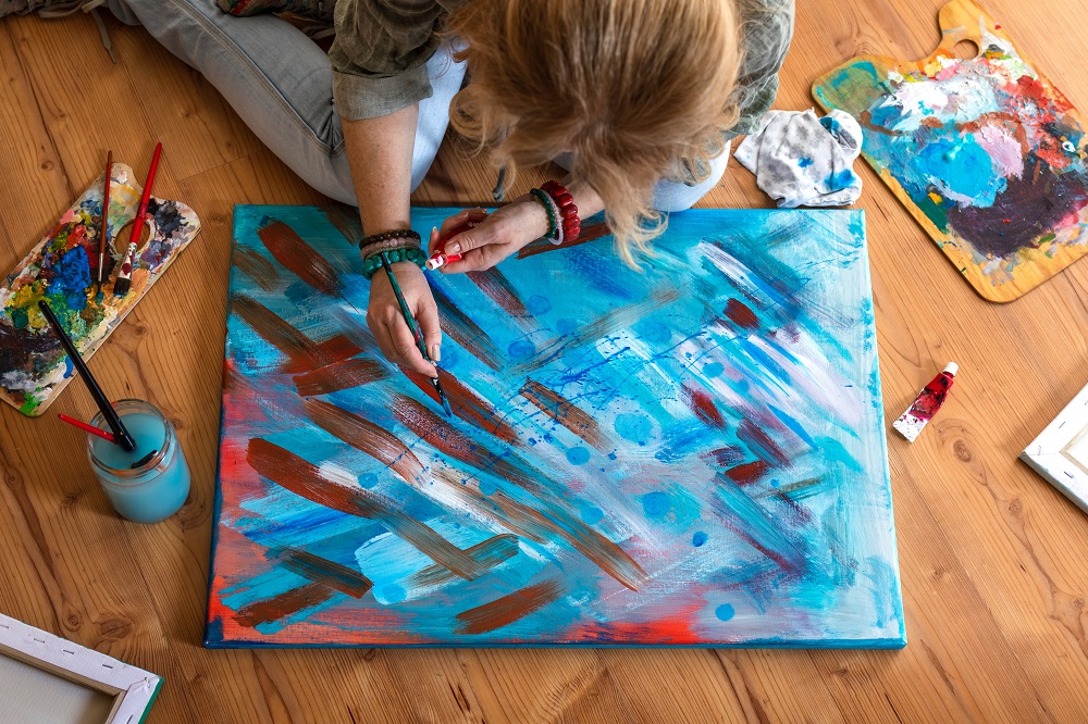 Woman paints abstract picture on floor