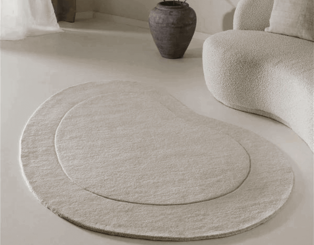 Elegant beige-coloured, abstractly shaped area rug on a minimalist white floor.